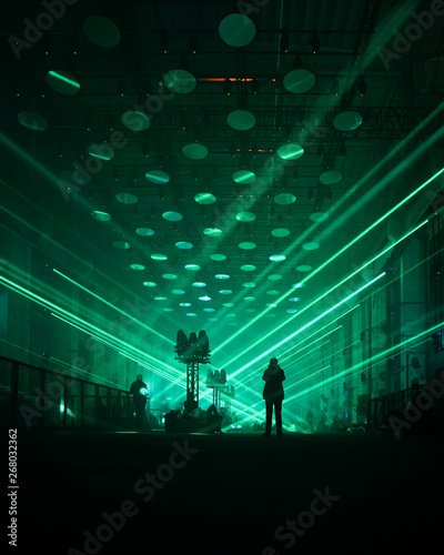 silhouette image of person standing on stage with green strobe lights