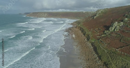 Aerial of Sennen Cove waves lapping at deserted beach turquoise sea dramatic cliffs and rocks photo