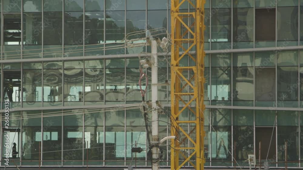 Steady, medium wide shot of people inside glass building and the middle of a crane. Steady, medium wide shot of people inside glass building and the middle of a crane.