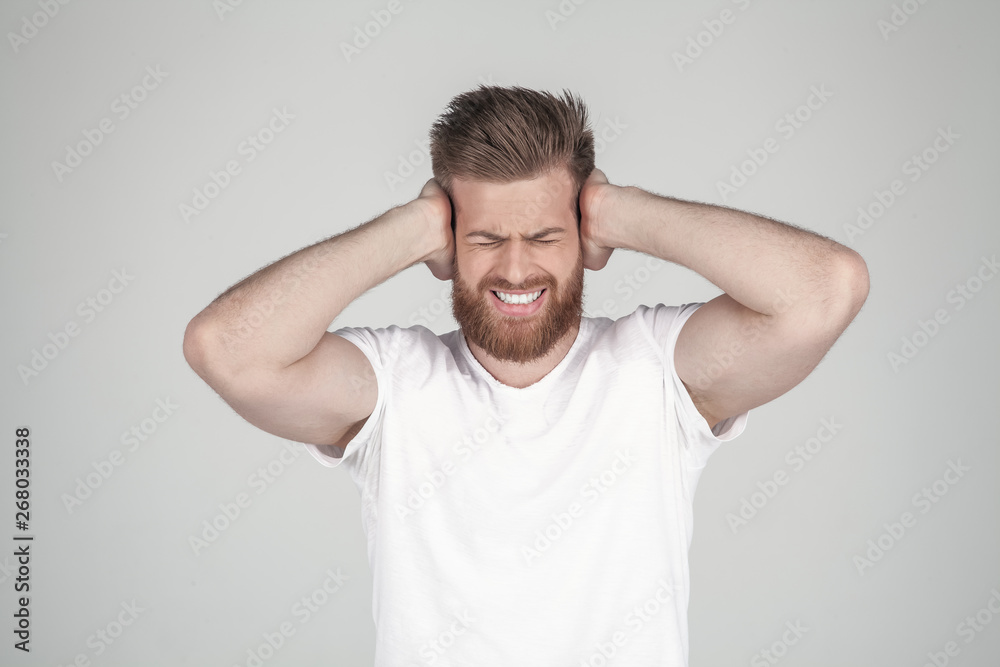 Portrait of beautiful sexy bearded man. holds his arms behind his head and shouts. he has a headache, he stands in front of the white background Portrait of beautiful sexy bearded man. holds his arms behind his head and shouts. he has a headache, he stands in front of the white background