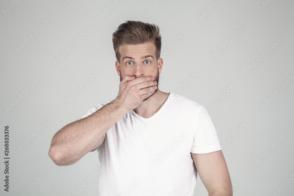 Portrait of beautiful sexy bearded man. closes the hand with his mouth. he stands in front of the white background Portrait of beautiful sexy bearded man. closes the hand with his mouth. he stands in front of the white background