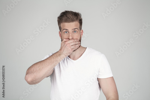 Portrait of beautiful sexy bearded man. closes the hand with his mouth. he stands in front of the white background