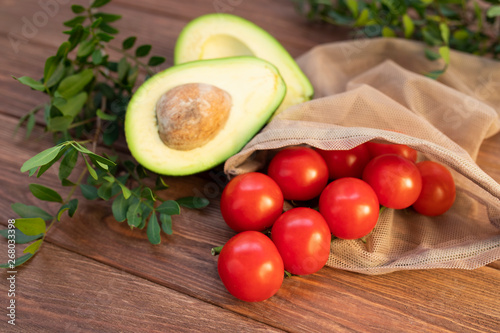 Ripe and fresh avocado and cherry tomatoes on a wooden background