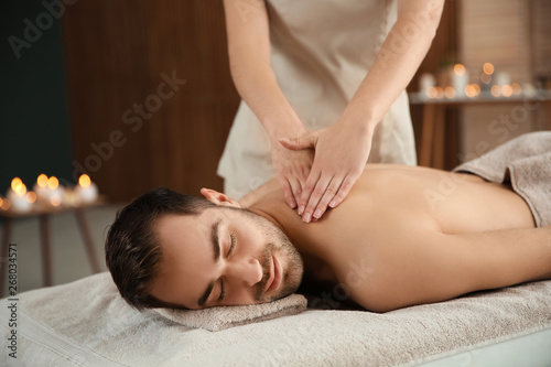Handsome man receiving back massage in spa salon