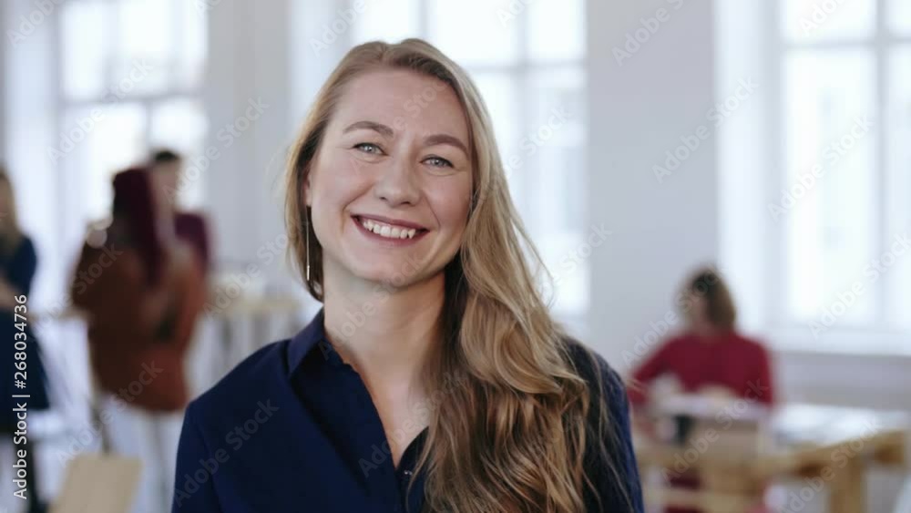 Close-up portrait of happy professional female boss with blond hair in formal clothes posing at trendy modern office.