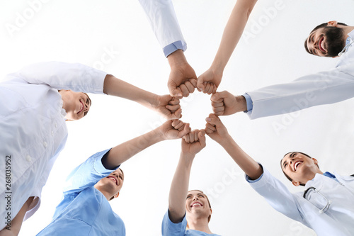 Team of medical doctors putting hands together on white background, closeup. Unity concept © New Africa