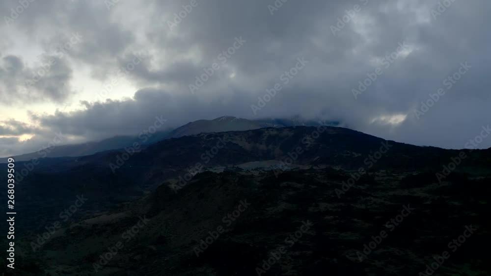 Aerial view of the Crater Volcano Aerial of through the Mountains and terrible clouds. 4K drone shot of the Teide. Flying over a beautiful cliffs black lava and bright skins on the sky of Spain Aerial view of the Crater Volcano Aerial of through the Mountains and terrible clouds. 4K drone shot of the Teide. Flying over a beautiful cliffs black lava and bright skins on the sky of Spain