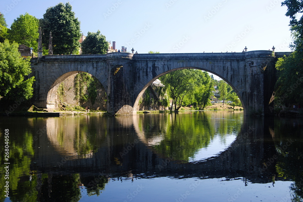 Ponte de pedra antiga reflectida no rio, cidade de Amarante no norte de Portugal