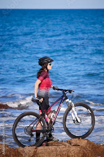 female cyclist with mountain bike on the coast