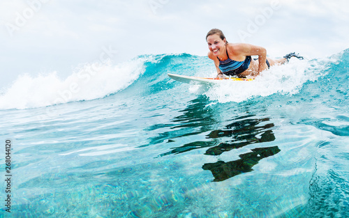 Photography Young woman surfer starts riding the turquoise ocean wave looks at the camera an