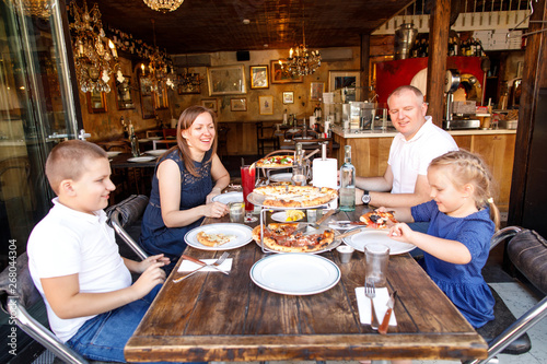 young family dad mom son and daughter eat tasty pizza in a restaurant