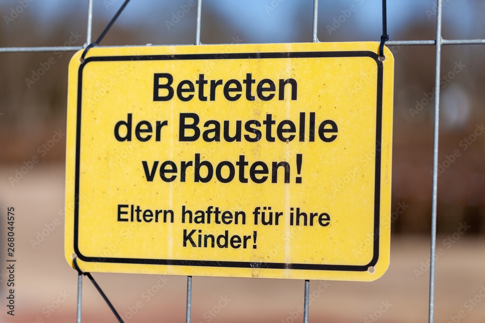 German construction side sign on a fence. Betreten der Baustelle verboten. Eltern haften für ihre Kinder, means no Trespassing. Parents are responsible for their children.