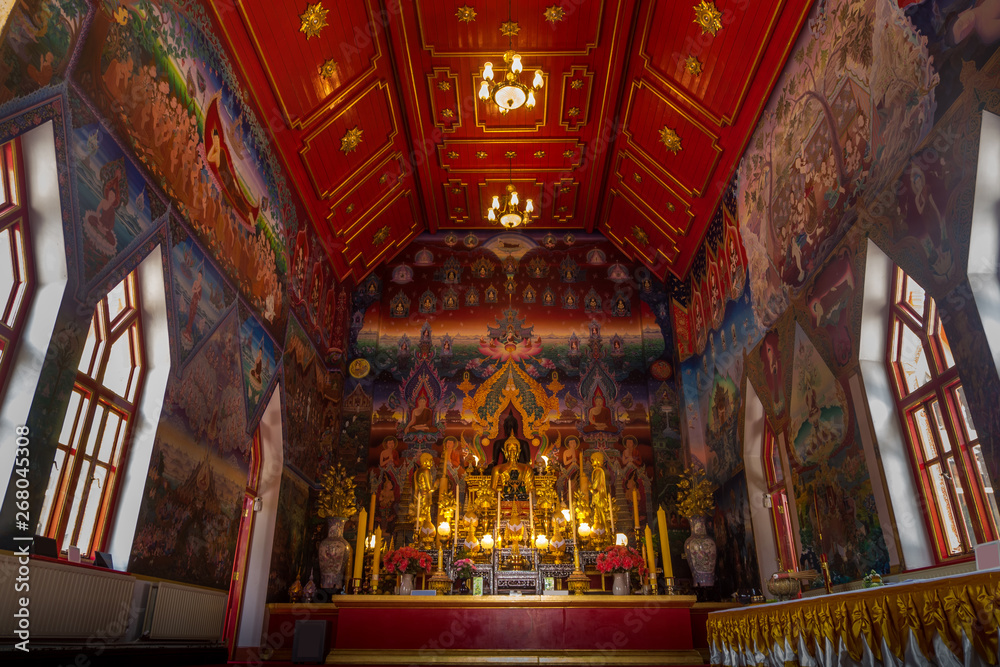 Within the church of the Buddhist temple, there is a Buddha image for worship and a painting on the church wall.