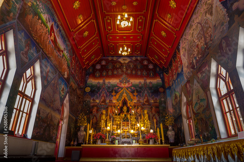 Within the church of the Buddhist temple, there is a Buddha image for worship and a painting on the church wall.