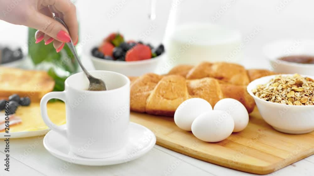 Female hand finishing mixing hot coffee using spoon ready to having breakfast meal close-up Female hand finishing mixing hot coffee using spoon ready to having breakfast meal close-up