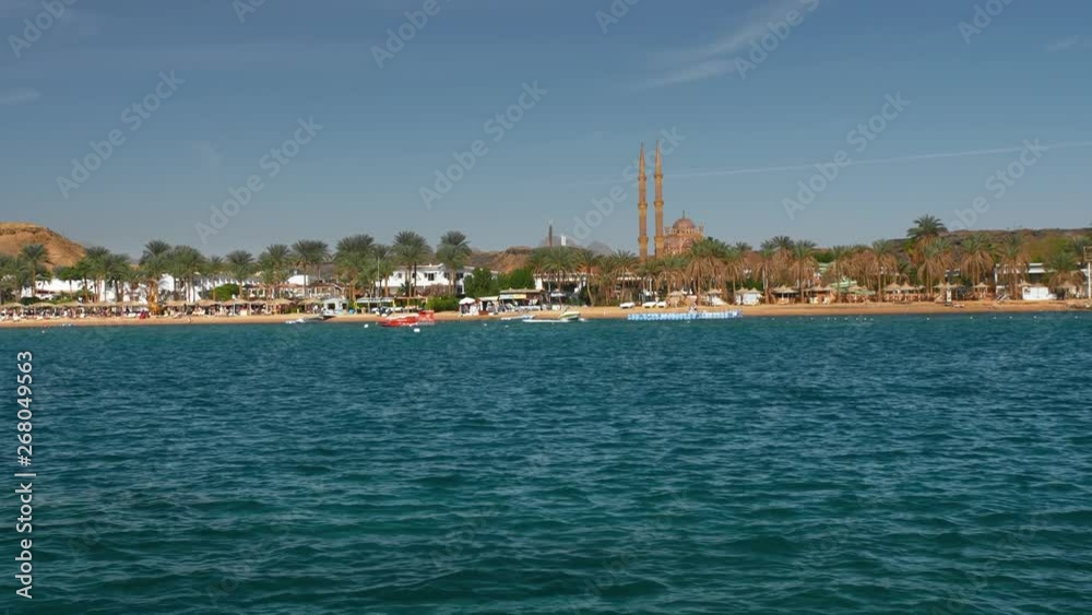 Movement speedboat on the blue beautiful sea in the summer on a sunny day. Against the backdrop of palm trees and resort hotels. A minaret and a mosque can be seen in the distance. Slow Motion. Movement speedboat on the blue beautiful sea in the summer on a sunny day. Against the backdrop of palm trees and resort hotels. A minaret and a mosque can be seen in the distance. Slow Motion.