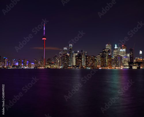 Toronto city skyline with lights on highrise towers at night reflected Lake Ontario