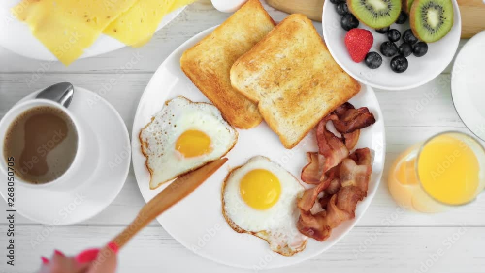 Top view female hand putting appetizing fried egg on plate between coffee and fresh juice POV shot Top view female hand putting appetizing fried egg on plate between coffee and fresh juice POV shot