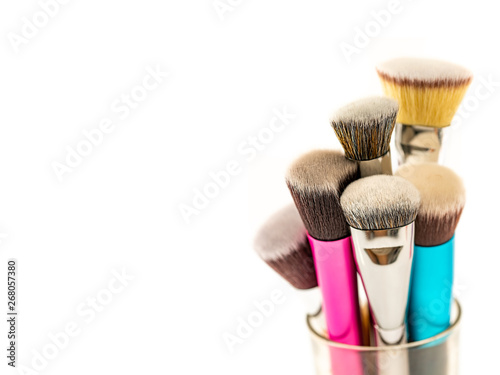 Collection of Cosmetic Foundation Brushes on Glass Jar Container with White Background. Double Fiber Bristle Makeup Foundation Brush. Close Up. Selective Focus.