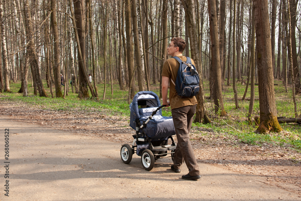 Young father walks with a baby carriage in the Park
