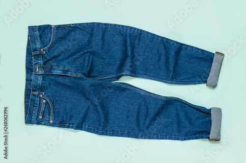 Men's jeans with cuffs on blue background. Flat lay.