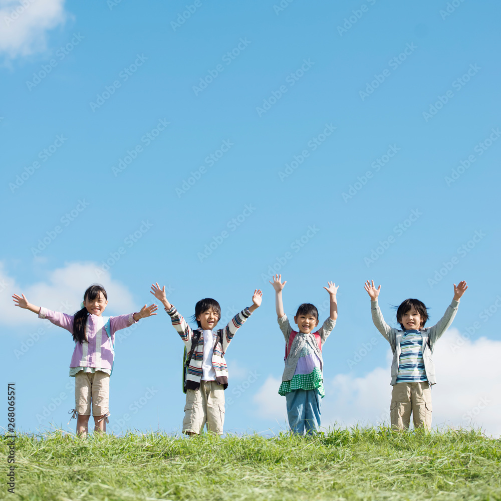 草原で両手を挙げる小学生