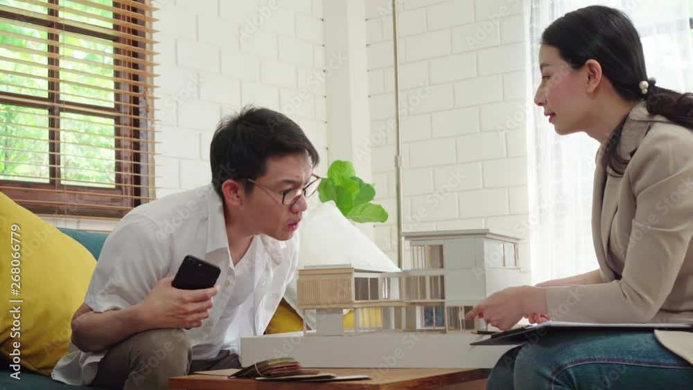 Asian housing broker presenting house model to customer for new house project