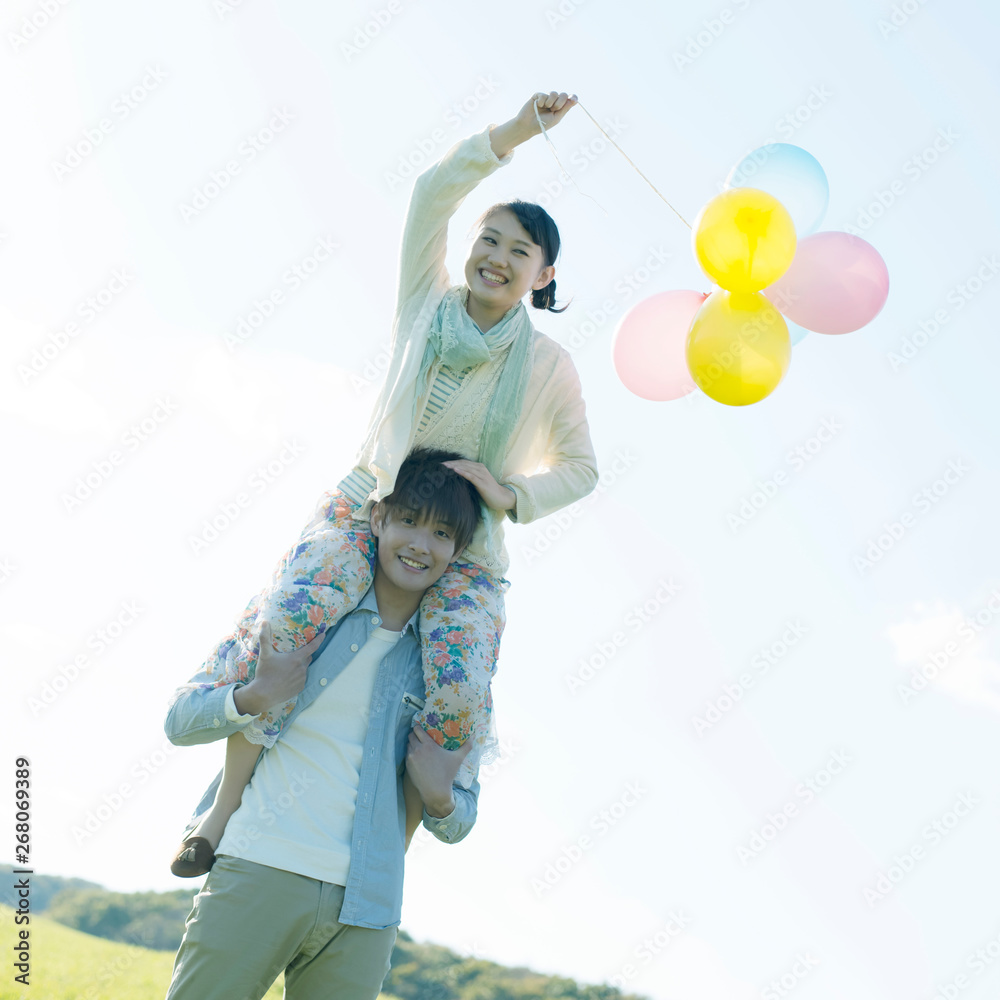 風船を持ち肩車をするカップル Stock Photo Adobe Stock