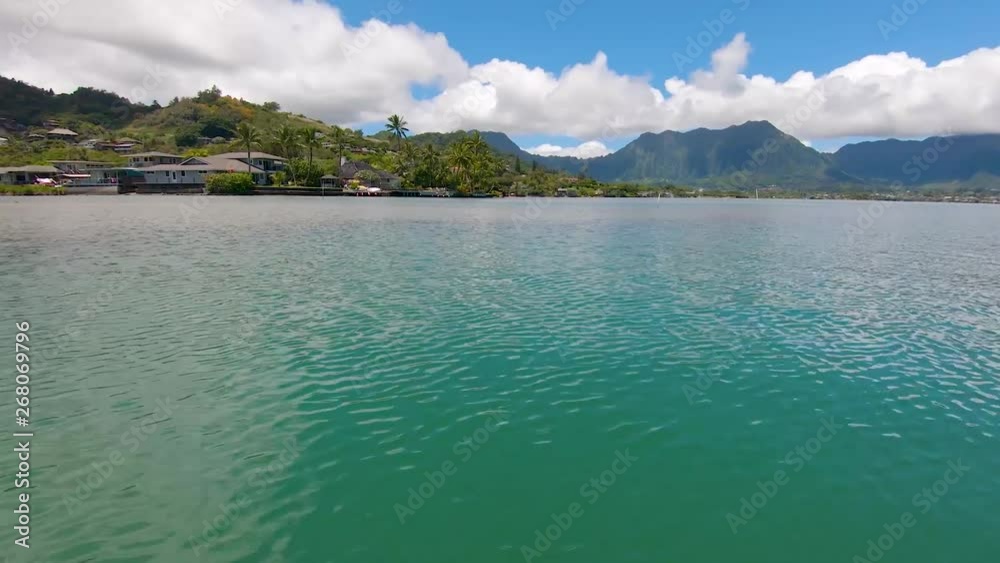 Gliding on green blue ocean, enjoying the views of Kaneohe Bay, Oahu, Hawaii and the Koolau mountains. Peaceful calm water is dreamy and serene on this tropical island paradise. Gliding on green blue ocean, enjoying the views of Kaneohe Bay, Oahu, Hawaii and the Koolau mountains. Peaceful calm water is dreamy and serene on this tropical island paradise.