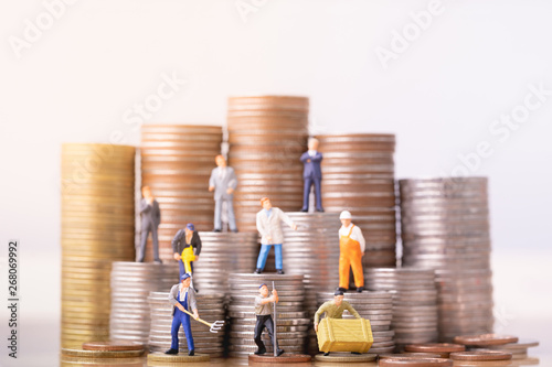 Miniature people standing on a pile of coins. Inequality and social class. Income and economic inequality concept. Inequality in social class, ideology, Gender, Racial and ethnic and health. photo