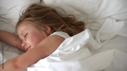 Little blond girl wakes up after a good sweet sleep