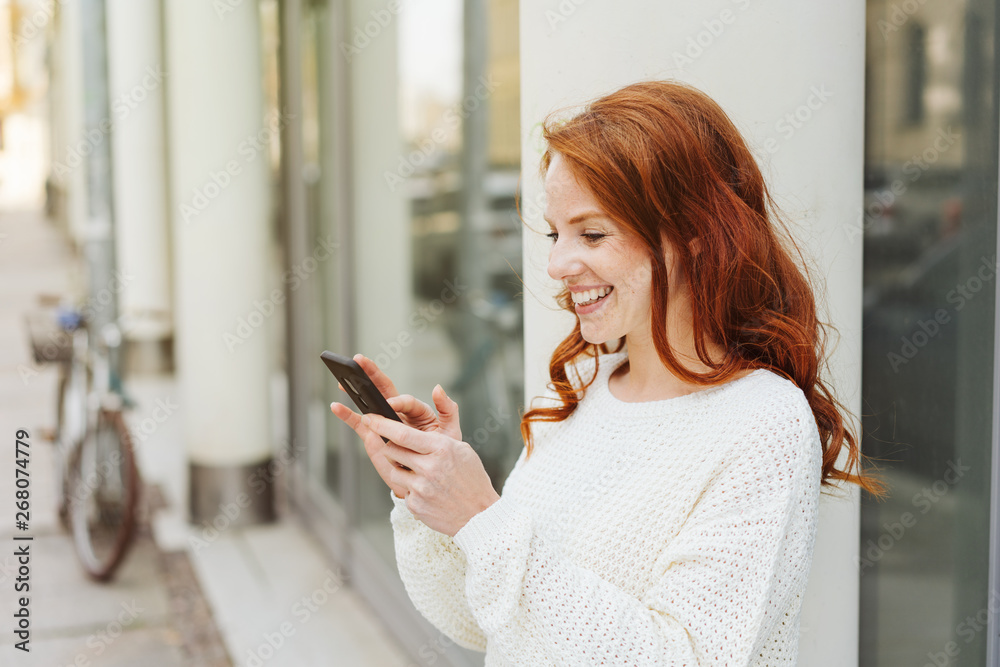 Happy young woman texting a message