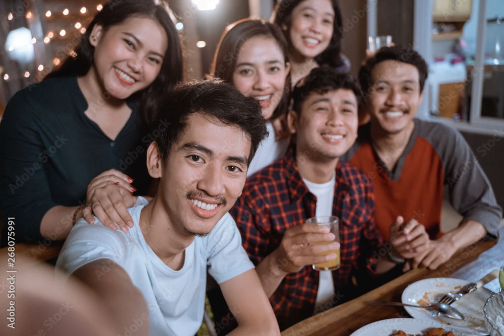Obraz premium asian bestfriend group take selfie with smartphone while having garden party dinner together