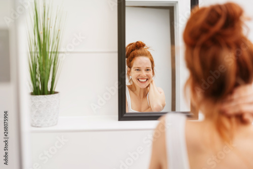 Happy young woman grinning at her reflection
