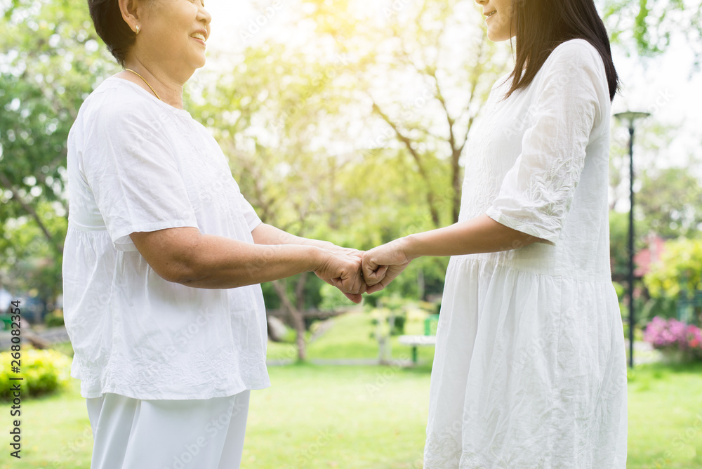 Hand of asian female elderly giving fist bump to hands young women at outdoor in garden,Happy and smiling Hand of asian female elderly giving fist bump to hands young women at outdoor in garden,Happy and smiling