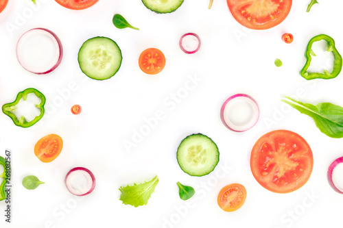 Fresh vegetable salad ingredients, shot from the top on a white background. A flat lay composition with tomato, pepper, cucumber, onion slices and mezclun leaves, forming a frame for copy space