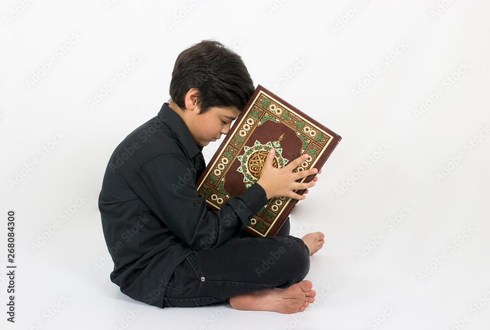Muslim young boy kissing Quran, the holy book of Islam Stock Photo