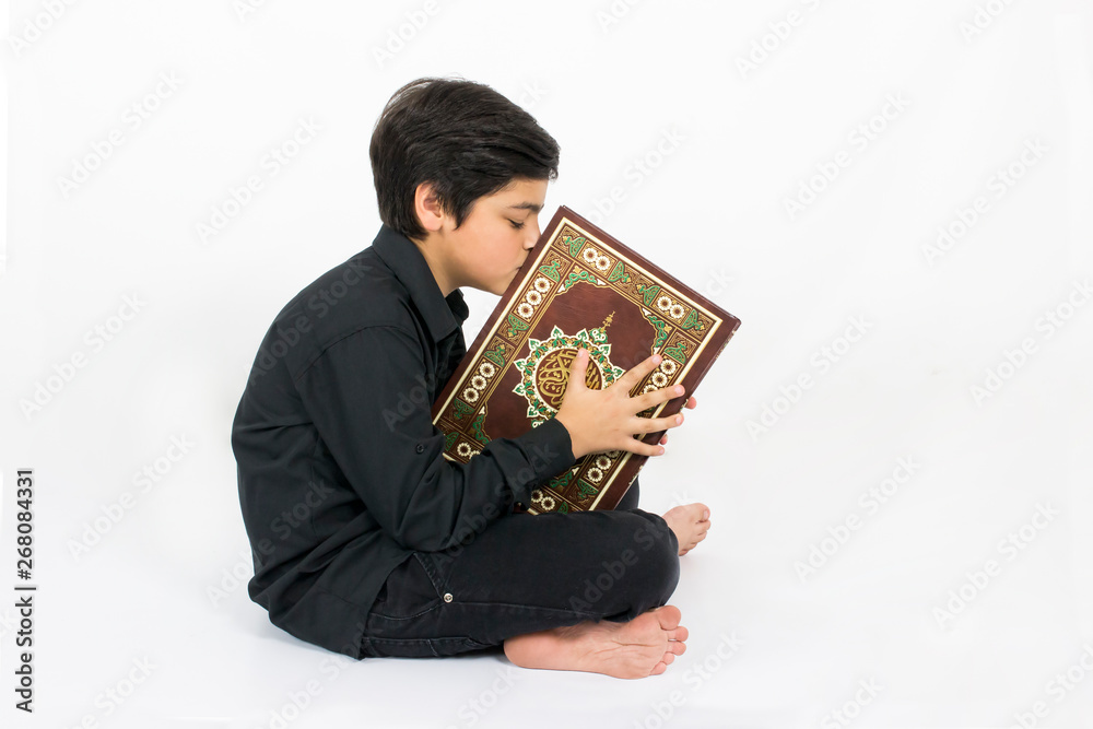 Muslim young boy kissing Quran, the holy book of Islam Stock Photo