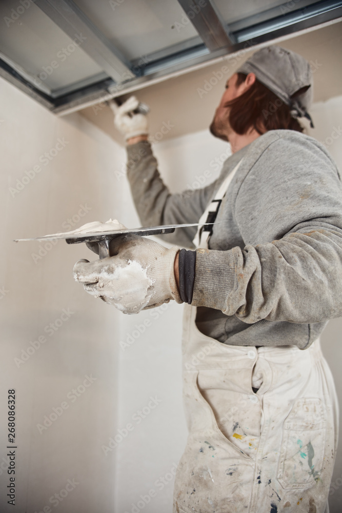 Workman plastering gypsum walls inside the house. Workman plastering gypsum walls inside the house.