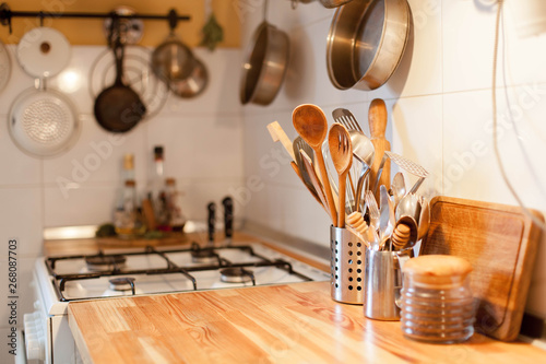 Kitchen scene with gas-cooker, dishes, wooden utensils, kitchenware, spoons. Cozy home background. photo