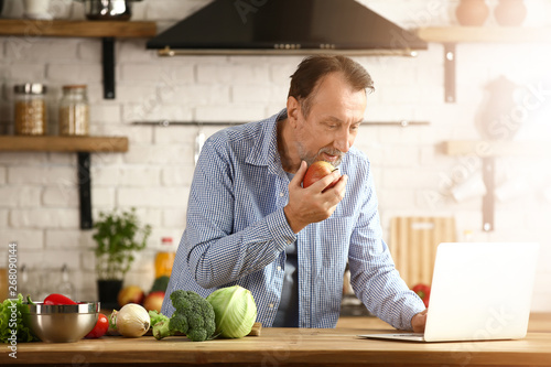 Handsome mature man with laptop in kitchen