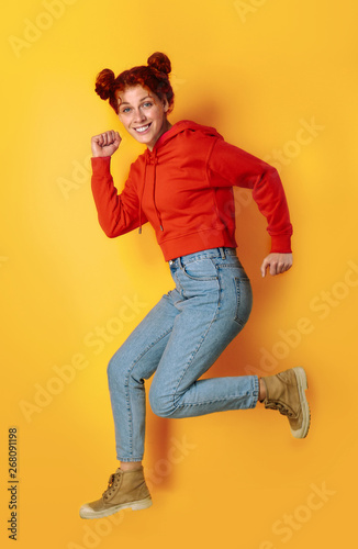 Beautiful jumping redhead woman on color background