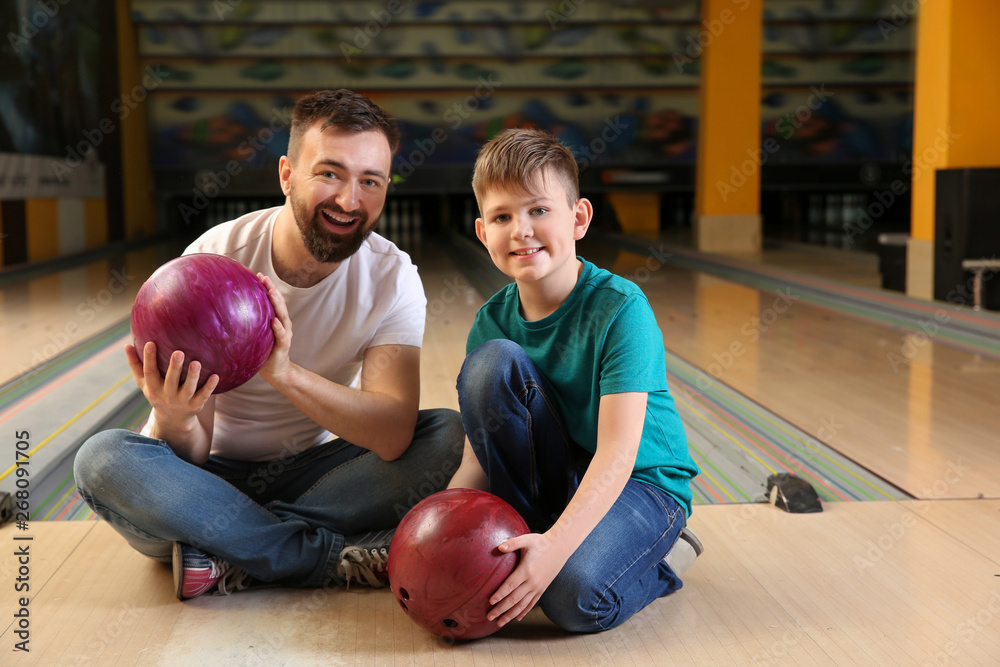 Fototapeta premium Man and his little son in bowling club