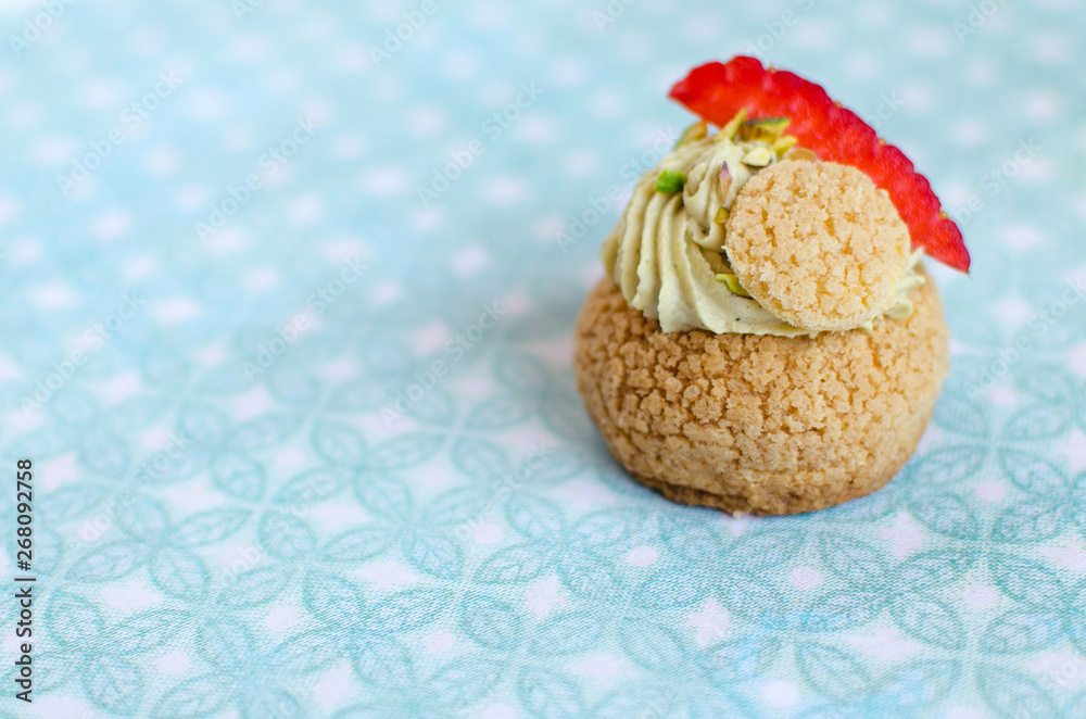 French traditional Choux pastry ball with pistachio cream and fresh strawberries on green background