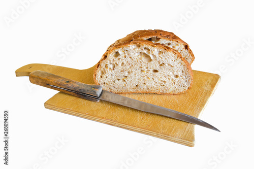 grain bread cut on a wooden cutting board with a bread knife on a white background