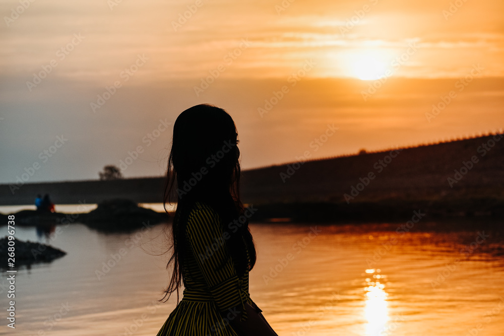 a beautiful girl standing in front of calm water and beautiful sunset sky at nyari dam, rajkot, India. 