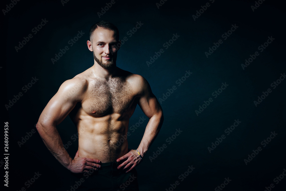 Obraz premium Low key portrait of muscular shirtless man at dark background
