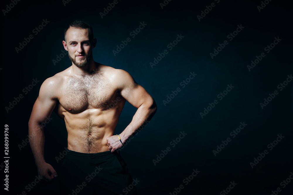 Low key portrait of muscular shirtless man at dark background
