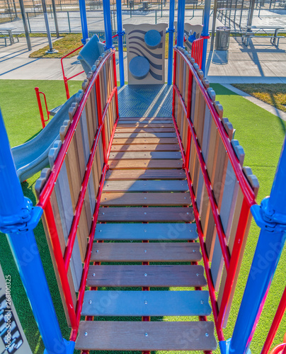 Playground equipment with a bridge and slide against vibrant green lawn © Jason