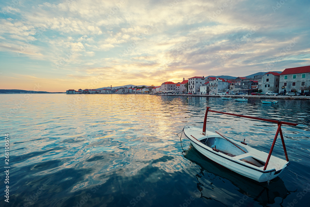 Beautiful sunset landscape. Fishing boat moored on Kastel coast in Dalmatia,Croatia.Old town near Adriatic sea.